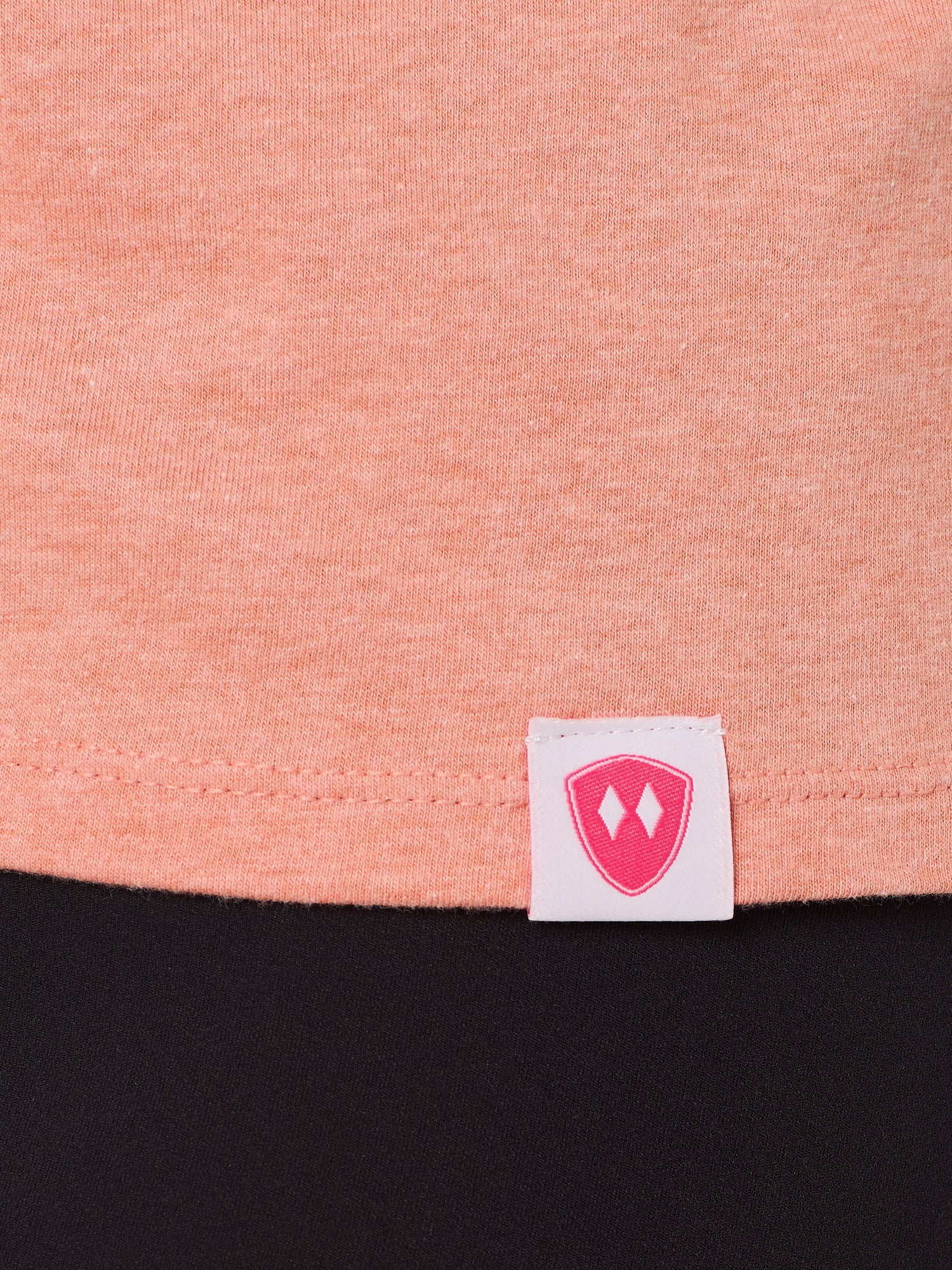 Close-up detail of a pink Double Diamond Shield woven hem label on a sunset tank.