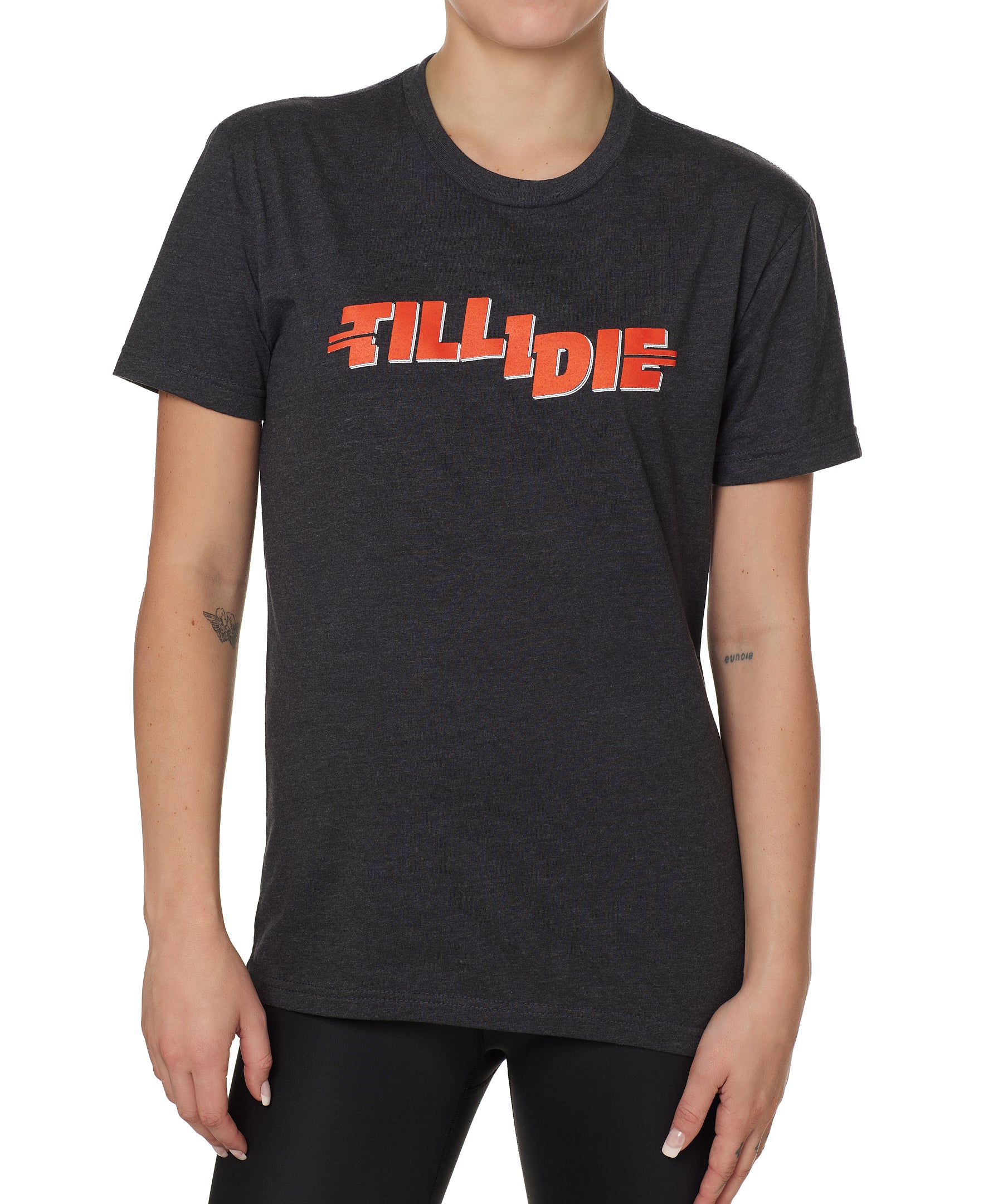 front view of a female model wearing the hot dog crew neck tee in heather charcoal. The graphic is red 'till i die' lettering inspired by the iconic title art for the 1984 ski move 'Hot Dog'