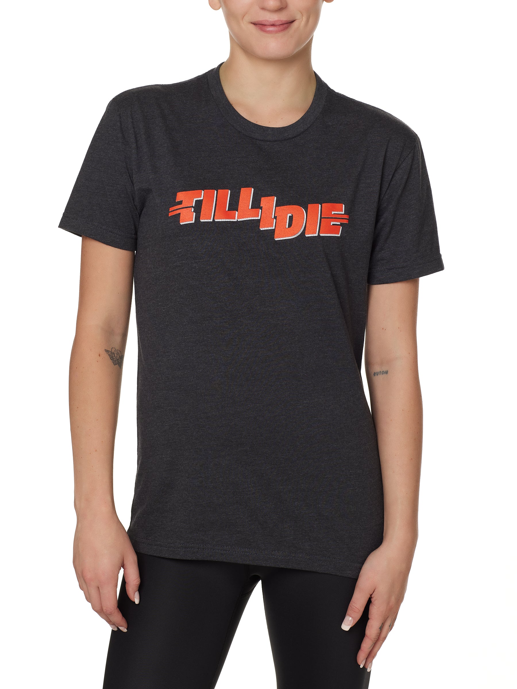 front view of a female model wearing the hot dog crew neck tee in heather charcoal. The graphic is red 'till i die' lettering inspired by the iconic title art for the 1984 ski move 'Hot Dog'
