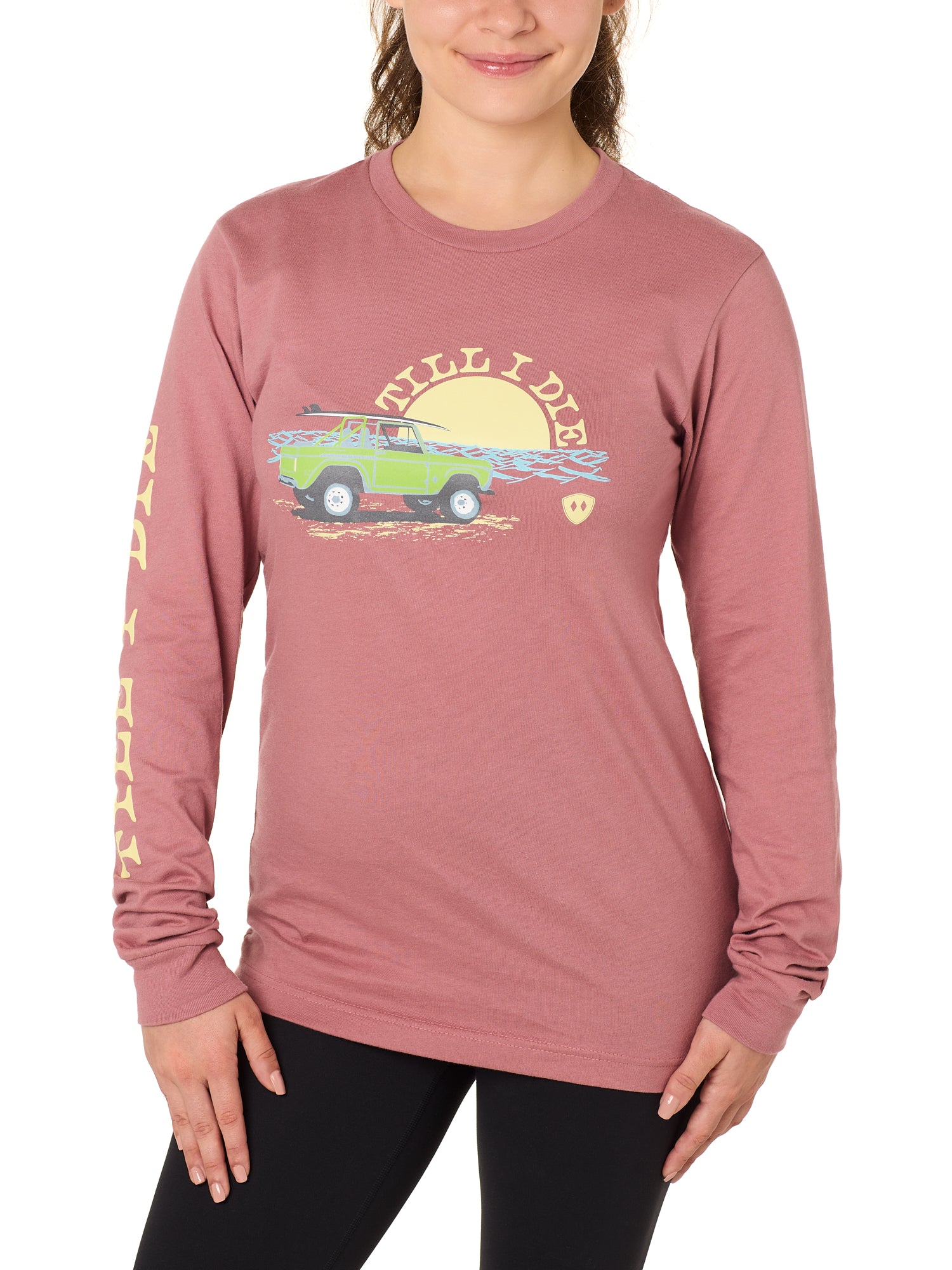 Front view of a female model wearing the Surf Truck long sleeve tee in deep sunset on a white background. The graphic features a classic green Bronco with a surfboard on the roof, parked in front of an ocean sunset, arched by “Till I Die” text.
