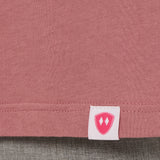 Close-up detail of a pink Double Diamond Shield woven hem label on a deep sunset long sleeve shirt.