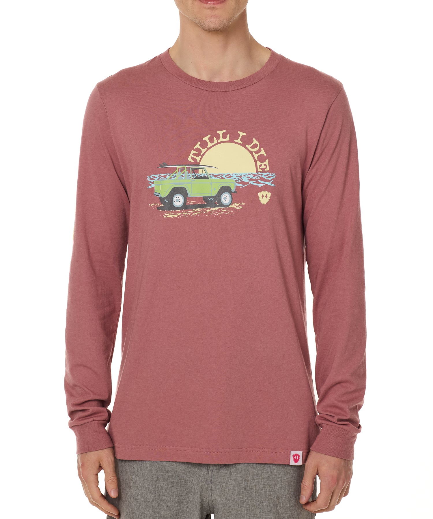 Front view of a male model wearing the Surf Truck long sleeve tee in deep sunset on a white background. The graphic features a classic green Bronco with a surfboard on the roof, parked in front of an ocean sunset, arched by “Till I Die” text.