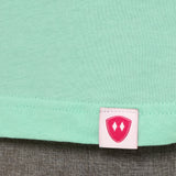 Close-up detail of a pink Double Diamond Shield woven hem label on a mint green shirt.