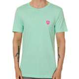 Front view of a male model wearing the Surfer Skeleton performance crew neck tee in mint green on a white background. Accented with a hot pink double diamond shield over wearers left chest.