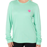 Front view of a female model wearing the Surfer Skeleton performance long sleeve tee in mint green on a white background. Accented with a hot pink double diamond shield over wearers left chest.