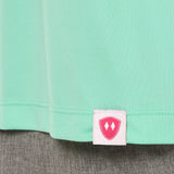 Close-up detail of a pink Double Diamond Shield woven hem label on a mint green performance long sleeve shirt.
