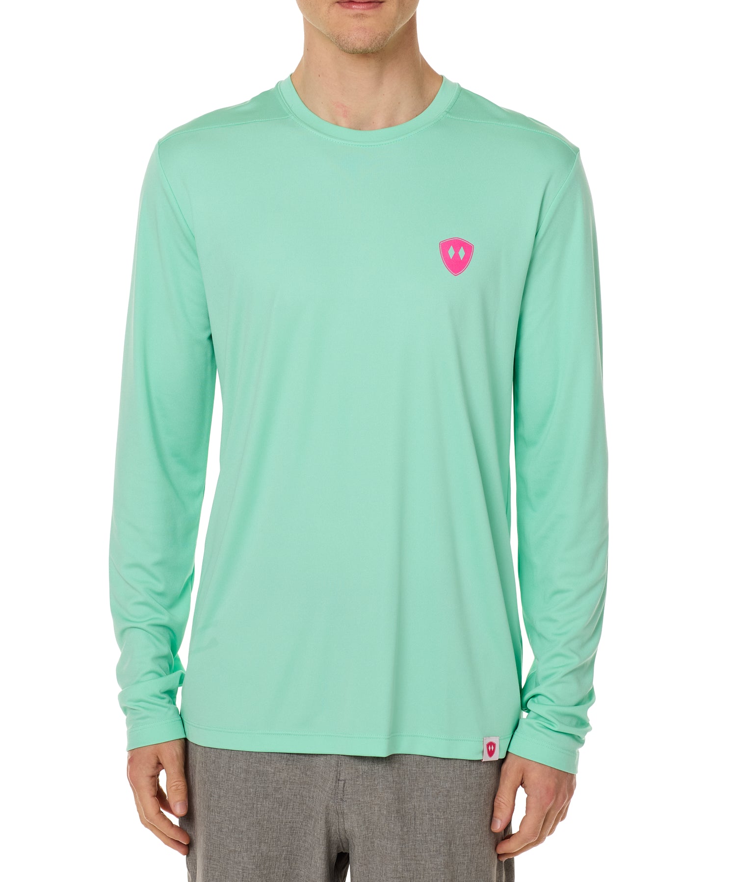 Front view of a male model wearing the Surfer Skeleton performance long sleeve tee in mint green on a white background. Accented with a hot pink double diamond shield over wearers left chest.