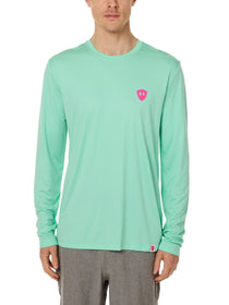 Front view of a male model wearing the Surfer Skeleton performance long sleeve tee in mint green on a white background. Accented with a hot pink double diamond shield over wearers left chest.