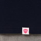 Close-up detail of a pink Double Diamond Shield woven hem label on a navy blue  shirt.
