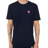 Front view of a male model wearing the Skull Wave Head crew neck tee in Navy on a white background. Accented with a hot pink double diamond shield over wearers left chest.