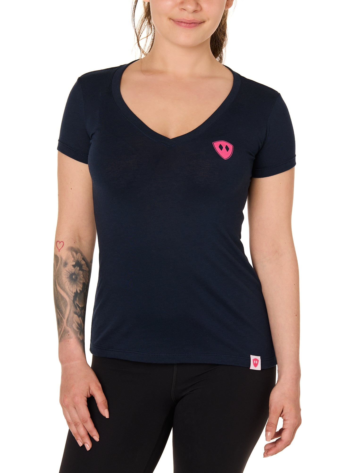 Front view of a female model wearing the Skull Wave Head V neck tee in mint green on a white background. Accented with a hot pink double diamond shield over wearers left chest.