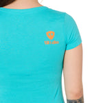 Back view of a female model wearing a Tahiti blue short sleeve shirt on a white background, featuring an orange Till I Die logo on the wearer’s top right shoulder.