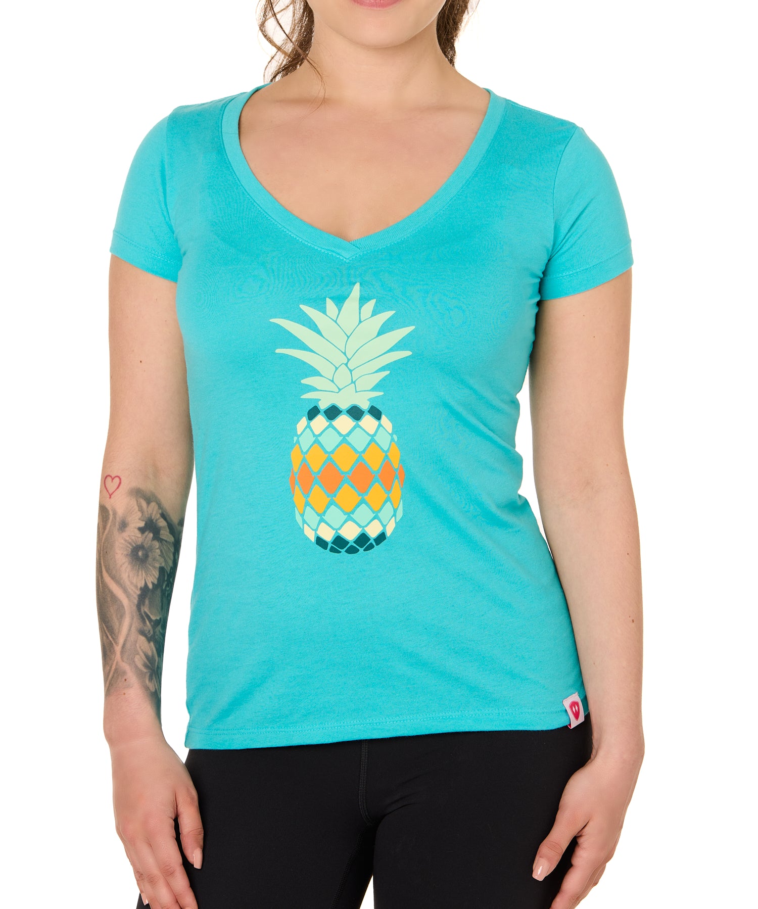 Front view of a female model wearing a Tahiti Blue short sleeve V neck t-shirt with a vibrantly colored retro pineapple graphic on the front.