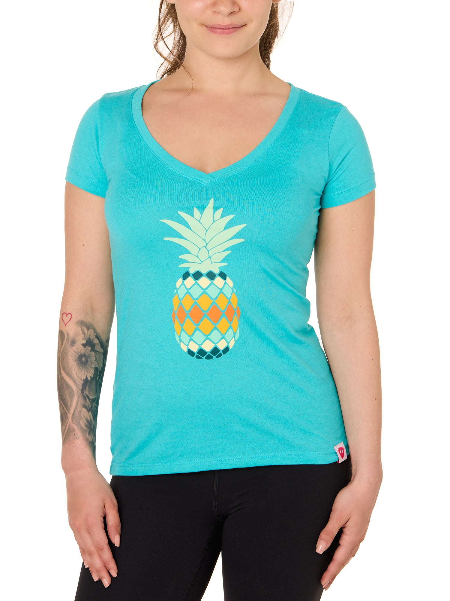 Front view of a female model wearing a Tahiti Blue short sleeve V neck t-shirt with a vibrantly colored retro pineapple graphic on the front.