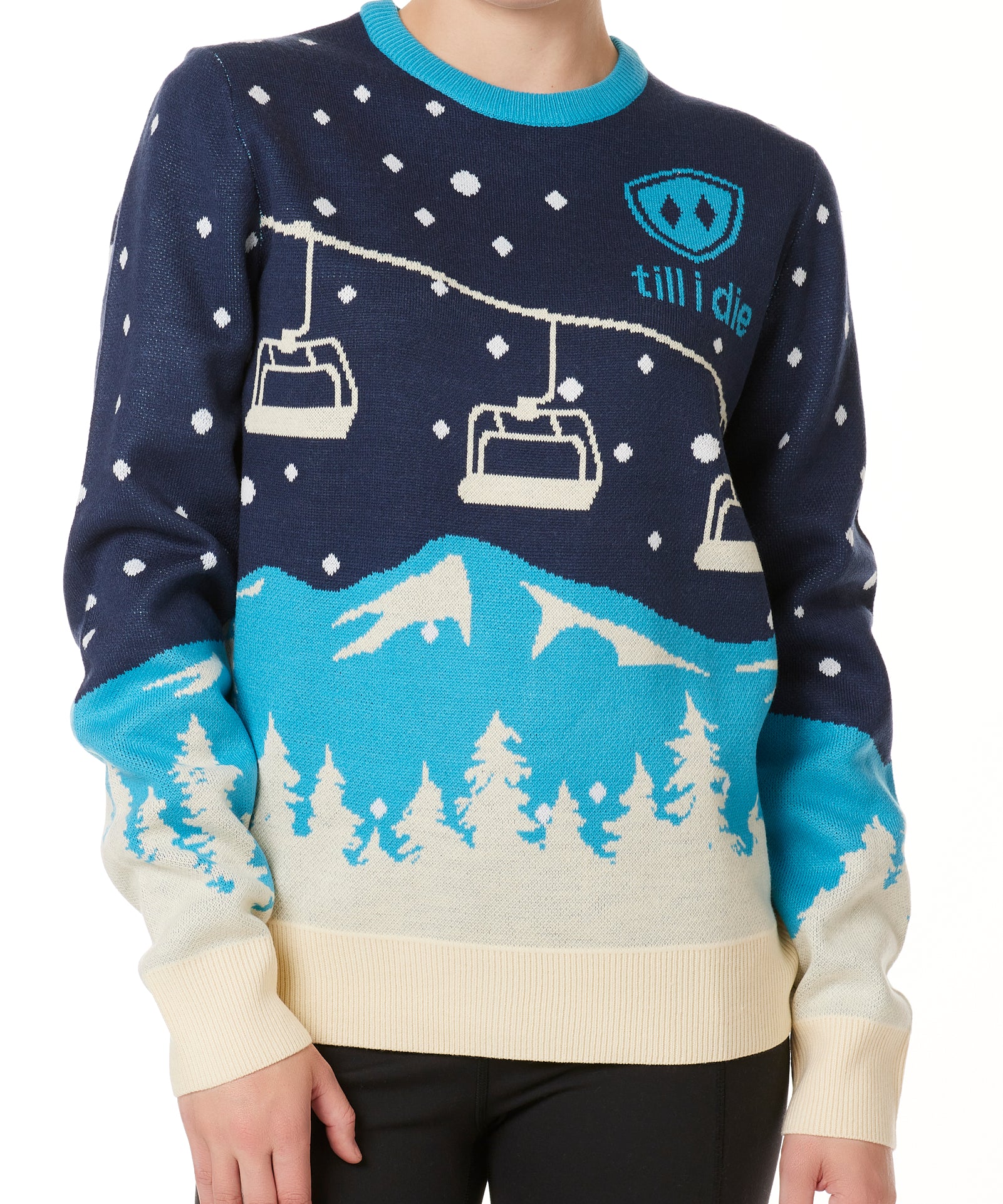 A woman wearing a navy and blue sweater with a snowy mountain and chairlift design.