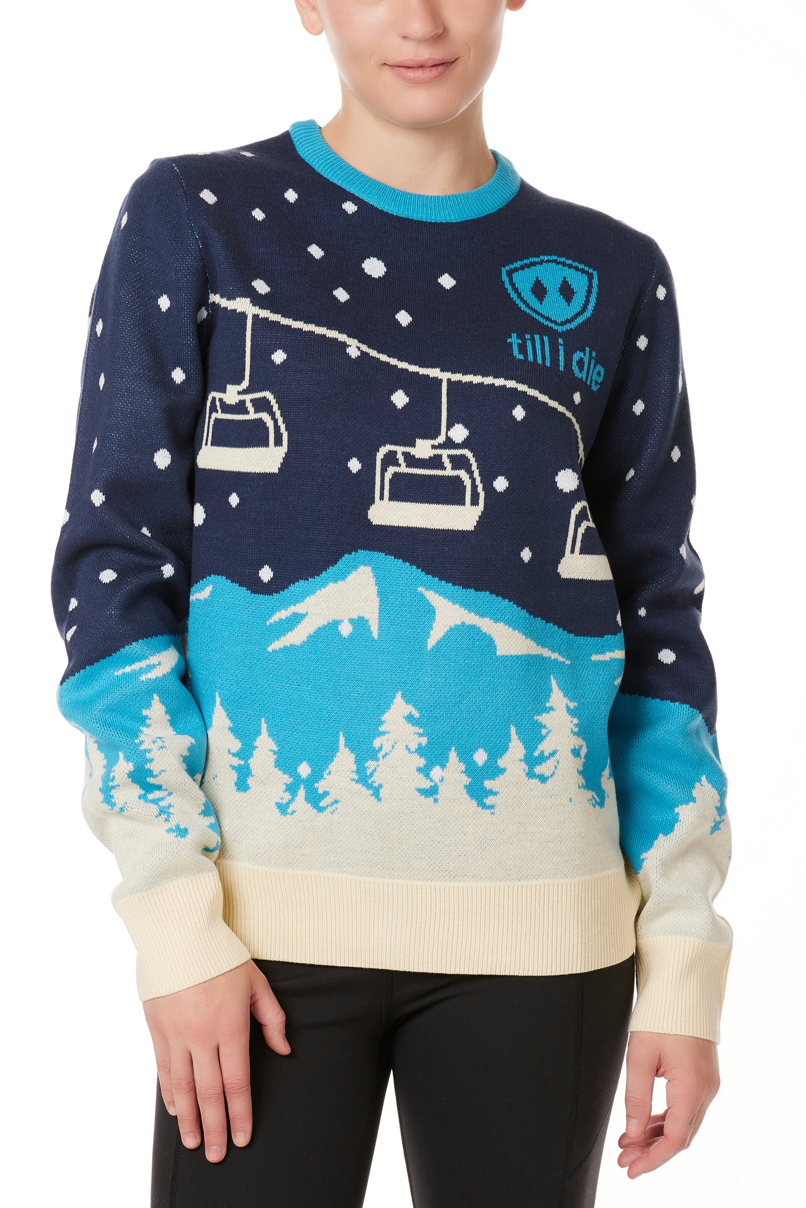 A woman wearing a navy and blue sweater with a snowy mountain and chairlift design.