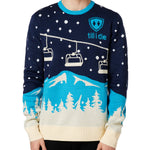 A male model wearing a blue and white 'Till I Die' brand pullover sweater with ski lift and mountain graphics.