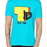 Front view of a male model wearing the TID TV crew neck tee in Tahiti Blue, displayed on a white background. The graphic features a large block-style yellow "T" alongside hand-drawn black "I" and "D" lettering, with "Till I Die" text beneath.