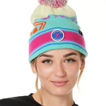 A WOMAN wearing a multicolored beanie with a pink pom-pom on top, featuring a TILL I DIE brand patch on the fold THAT SAYS "DO WHAT YOU LOVE. DO IT FOREVER."