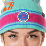 DETAIL A WOMAN wearing a multicolored beanie with a pink pom-pom on top, featuring a TILL I DIE brand patch on the fold THAT SAYS "DO WHAT YOU LOVE. DO IT FOREVER."