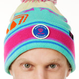 DETAIL A MAN wearing a multicolored beanie with a pink pom-pom on top, featuring a TILL I DIE brand patch on the fold THAT SAYS "DO WHAT YOU LOVE. DO IT FOREVER."