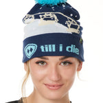 FEMALE MODEL WEARING A NAVY AND WHITE HAT WITH A BLUE POM POM AND CHAIRLIFT GRAPHIC WITH THE WORD "TILL I DIE" ON THE FOLD