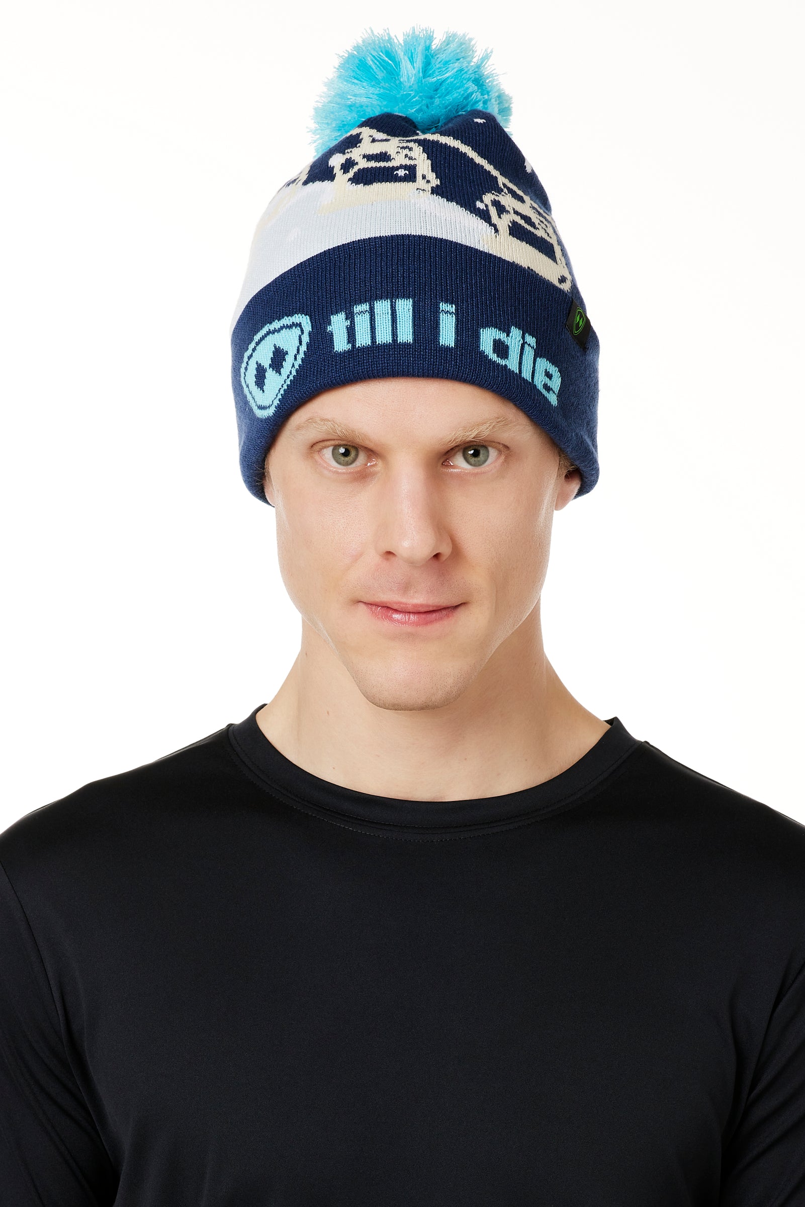 MALE MODEL WEARING A NAVY AND WHITE HAT WITH A BLUE POM POM AND CHAIRLIFT GRAPHIC WITH THE WORD "TILL I DIE" ON THE FOLD