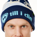 DETAIL OF A MALE MODEL WEARING A NAVY AND WHITE HAT WITH A BLUE POM POM AND CHAIRLIFT GRAPHIC WITH THE WORD "TILL I DIE" ON THE FOLD