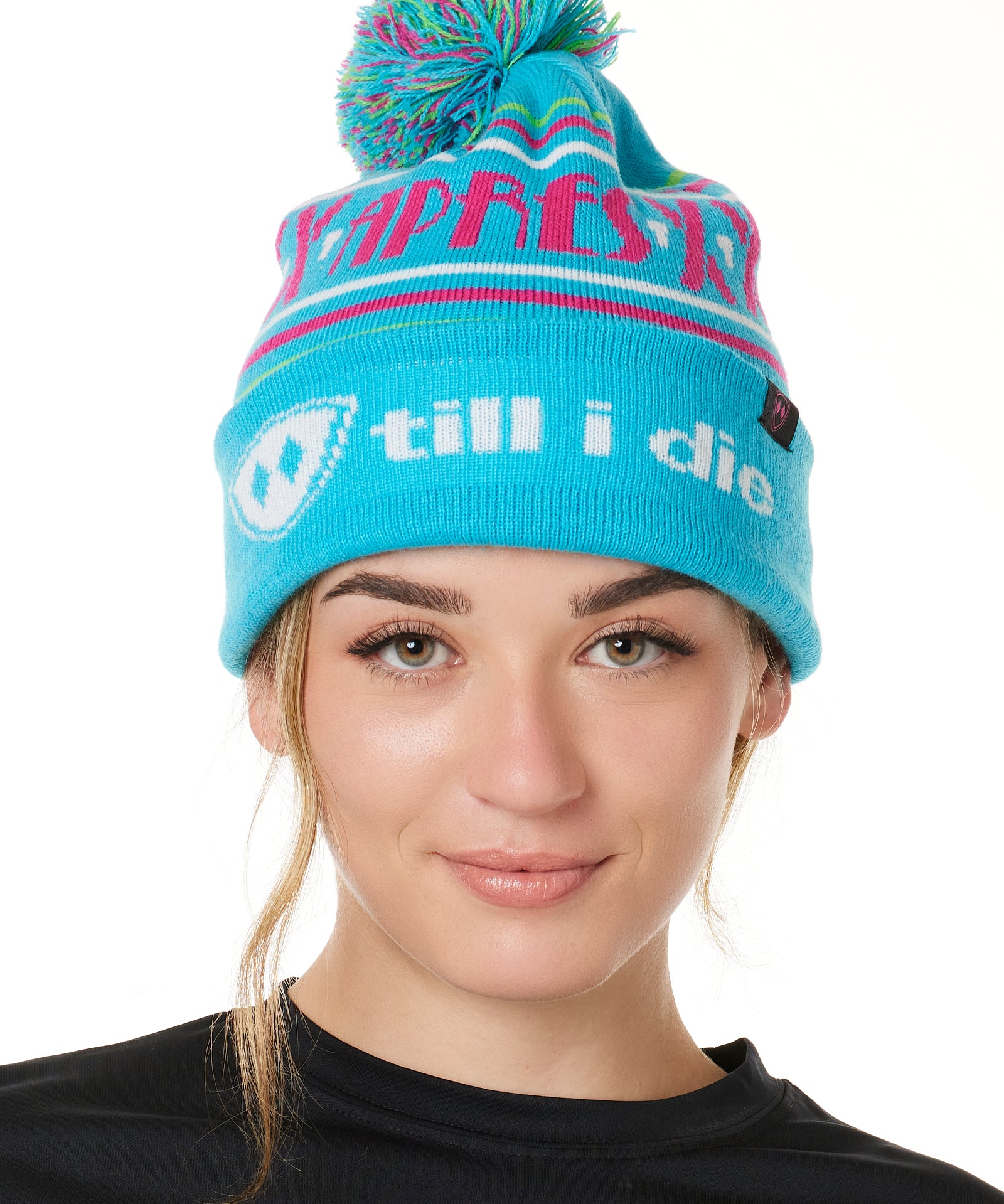 FEMALE MODEL WEARING A TEAL AND PINK HAT WITH A POM POM AND THE WORDS "APRES SKI"