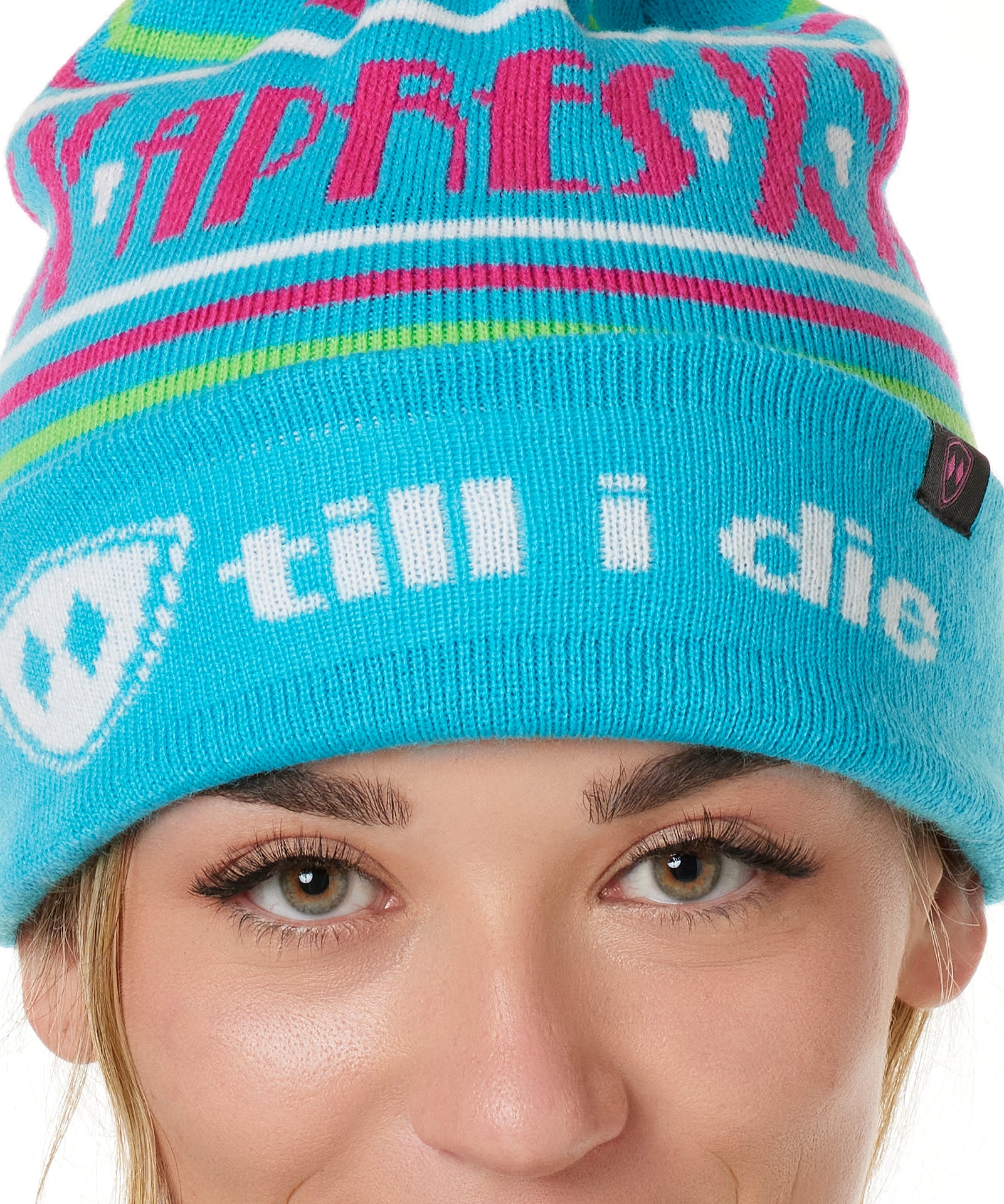 DETAIL OF A FEMALE MODEL WEARING A TEAL AND PINK HAT WITH A POM POM AND THE WORDS "APRES SKI"