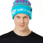 MALE MODEL WEARING A TEAL AND PINK HAT WITH A POM POM AND THE WORDS "APRES SKI"