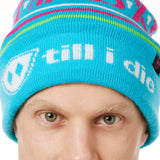 DETAIL OF A MALE MODEL WEARING A TEAL AND PINK HAT WITH A POM POM AND THE WORDS "APRES SKI"