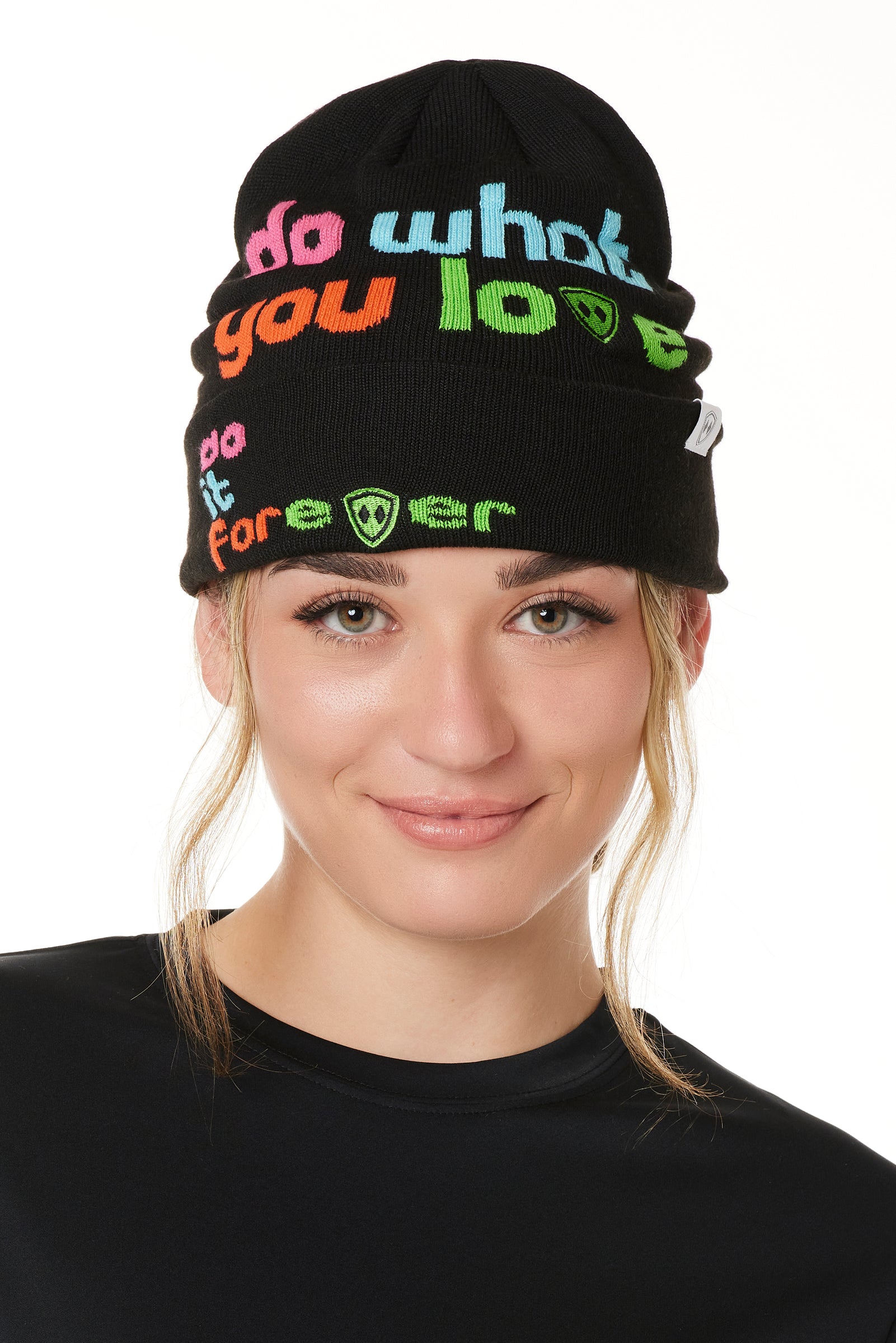 FEMALE MODEL WEARING A BLACK BEANIE WITH MULTICOLORED WORDS SAYING "DO WHAT YOU LOVE. DO IT FOREVER" 
