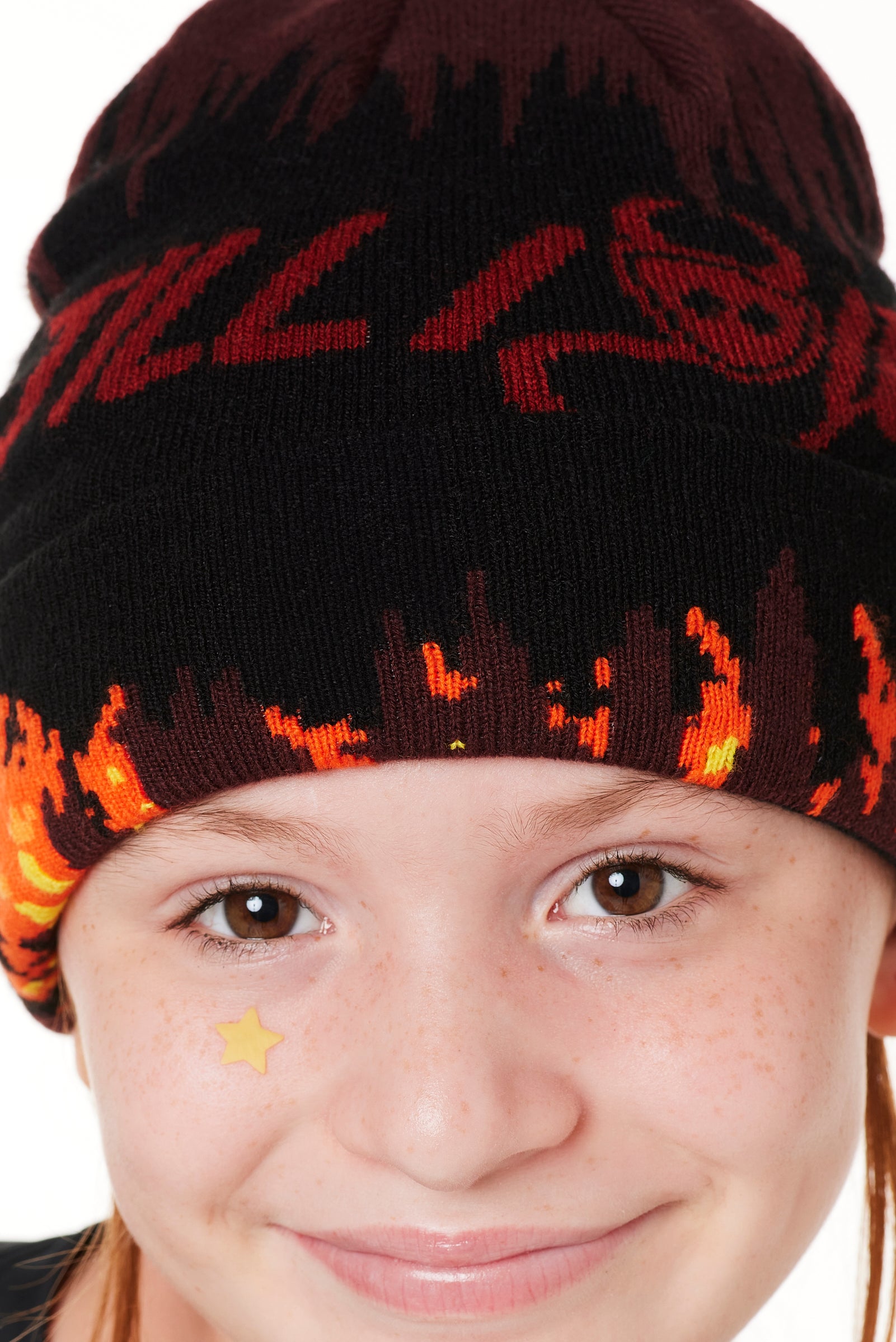 DETAIL OF A YOUTH MODEL WEARING A BEANIE HAT WITH FLAMES AND THE WORDS "TILL I DIE"
