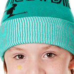 DETAIL OF A YOUTH MODEL  WEARING A MINT GREEN BEANIE WITH A WHITE POM POM AND THE GRAPHIC OF A SKIER