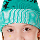DETAIL OF A YOUTH MODEL  WEARING A MINT GREEN BEANIE WITH A WHITE POM POM AND THE GRAPHIC OF A SKIER