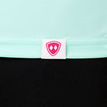 DETAIL OF A MINT GREEN LONG SLEEVE BASE LAYER WITH THE TILL I DIE SHIELD LOGO WOVEN LABEL ON THE HEM