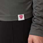 DETAIL OF A GRAY LONG SLEEVE BASE LAYER WITH THE TILL I DIE SHIELD LOGO WOVEN LABEL ON THE HEM