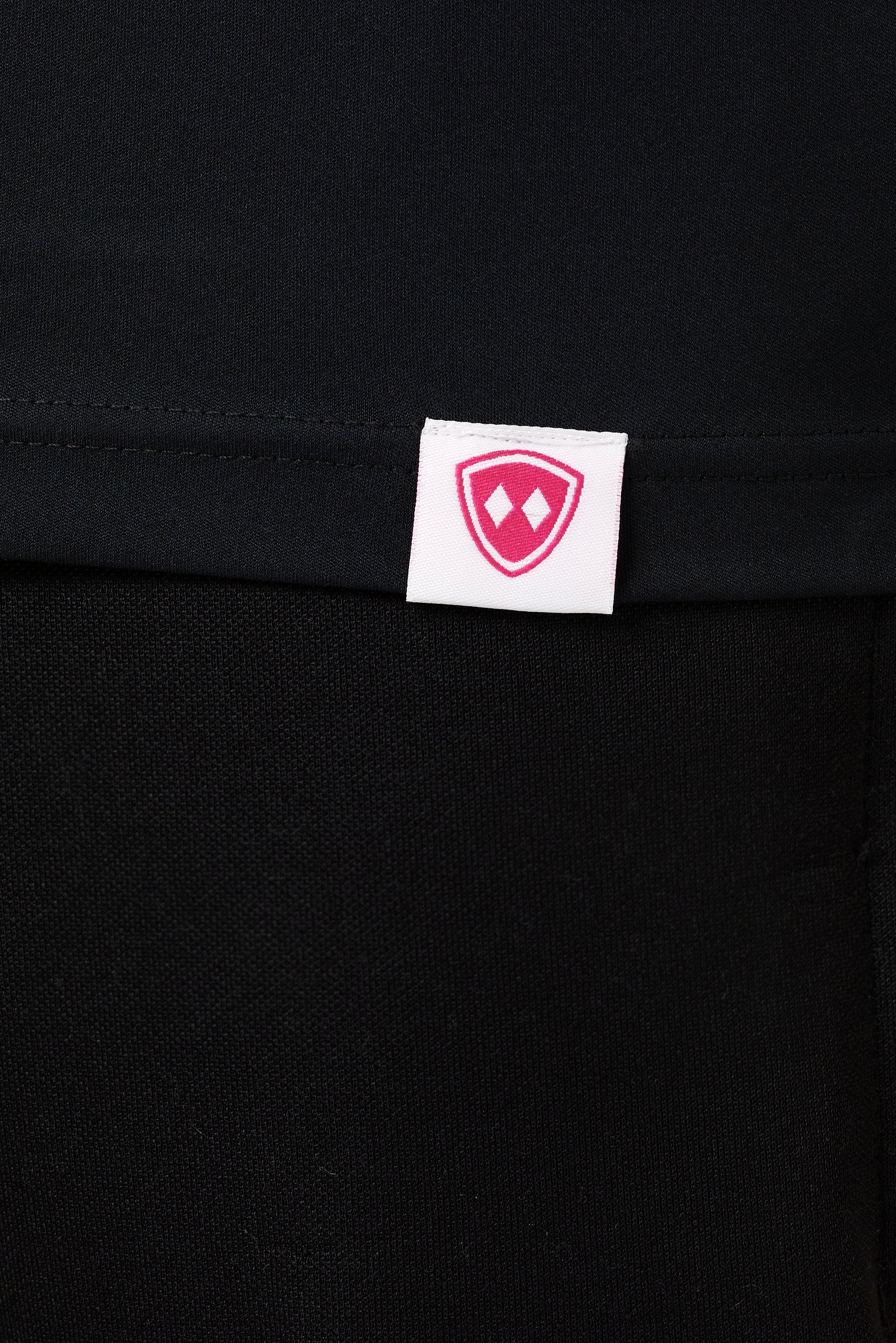 DETAIL OF A BLACK LONG SLEEVE BASE LAYER WITH THE TILL I DIE SHIELD LOGO WOVEN LABEL ON THE HEM