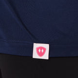 Close-up detail of a pink Double Diamond Shield woven hem label on a navy blue performance long sleeve shirt.