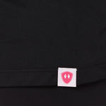 Close-up detail of a pink Double Diamond Shield woven hem label on a black performance long sleeve shirt.