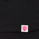 Close-up detail of a pink Double Diamond Shield woven hem label on a black performance long sleeve shirt.