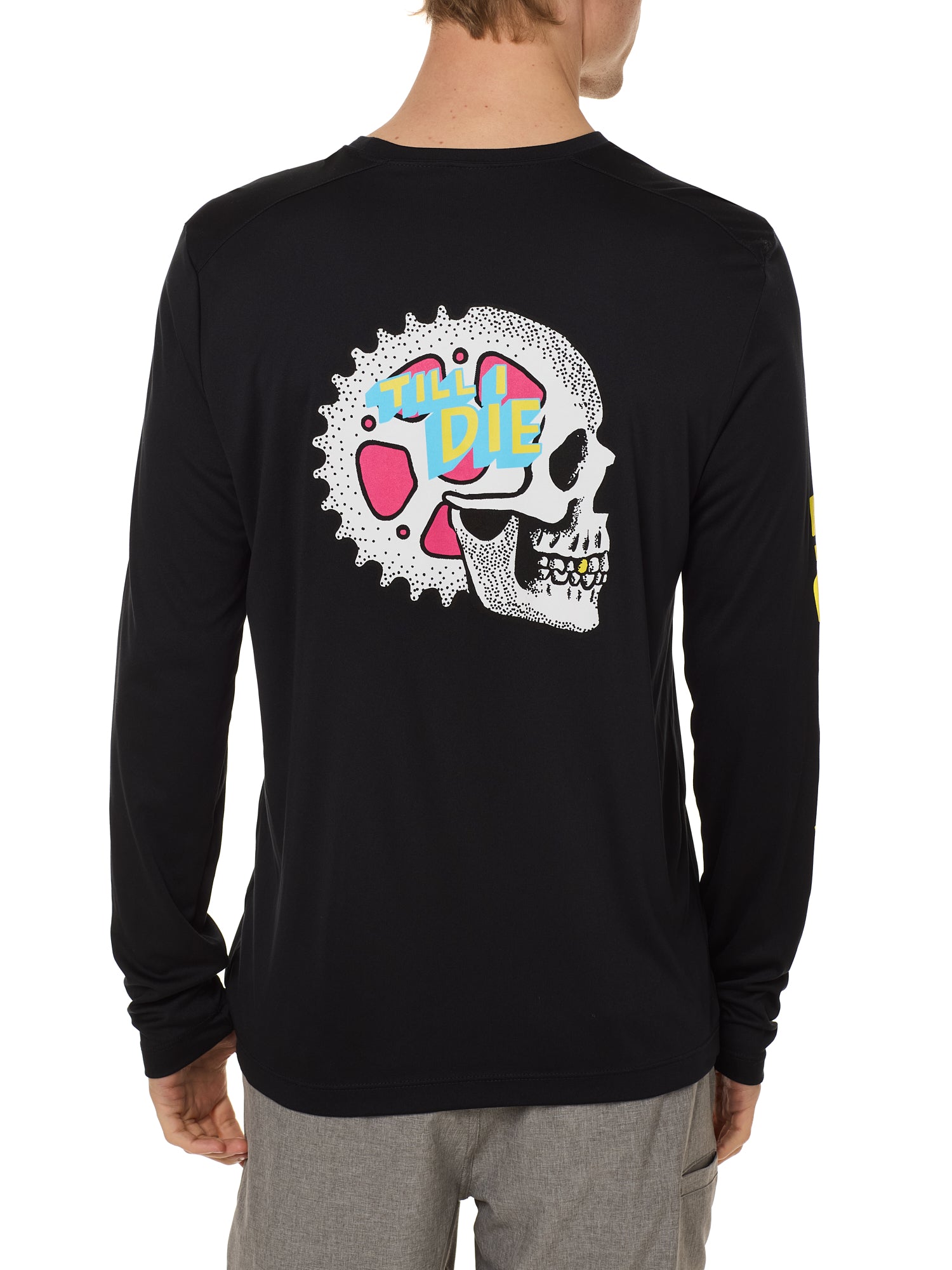 Back view of a male model wearing the Gear Head performance long sleeve Tee in black. The back graphic features a skull with gears inside the head and overlapped by yellow and blue "Till I Die" text.