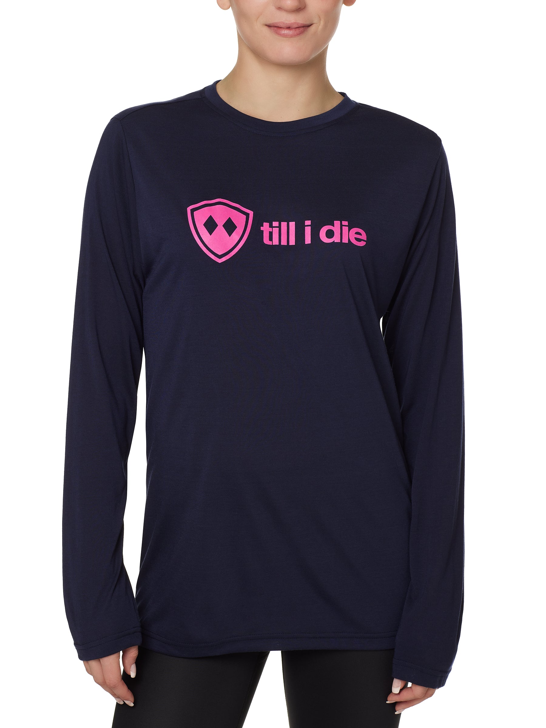 front view of a female model wearing a navy blue long sleeve tee with a hot pink till i die logo across the chest