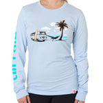 Front view of a female model wearing the Hammock long sleeve tee in light blue, displayed on a white background. The graphic depicts a vintage VW bus parked on a beach, with a surfboard leaning against it and a silhouetted figure relaxing in a hammock strung between the van and a palm tree.