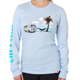 Front view of a female model wearing the Hammock long sleeve tee in light blue, displayed on a white background. The graphic depicts a vintage VW bus parked on a beach, with a surfboard leaning against it and a silhouetted figure relaxing in a hammock strung between the van and a palm tree.