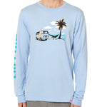 Front view of a male model wearing the Hammock long sleeve tee in light blue, displayed on a white background. The graphic depicts a vintage VW bus parked on a beach, with a surfboard leaning against it and a silhouetted figure relaxing in a hammock strung between the van and a palm tree.