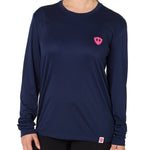 Front view of a female model wearing the Skull Wave Head performance long sleeve tee in Navy on a white background. Accented with a hot pink double diamond shield over wearers left chest.