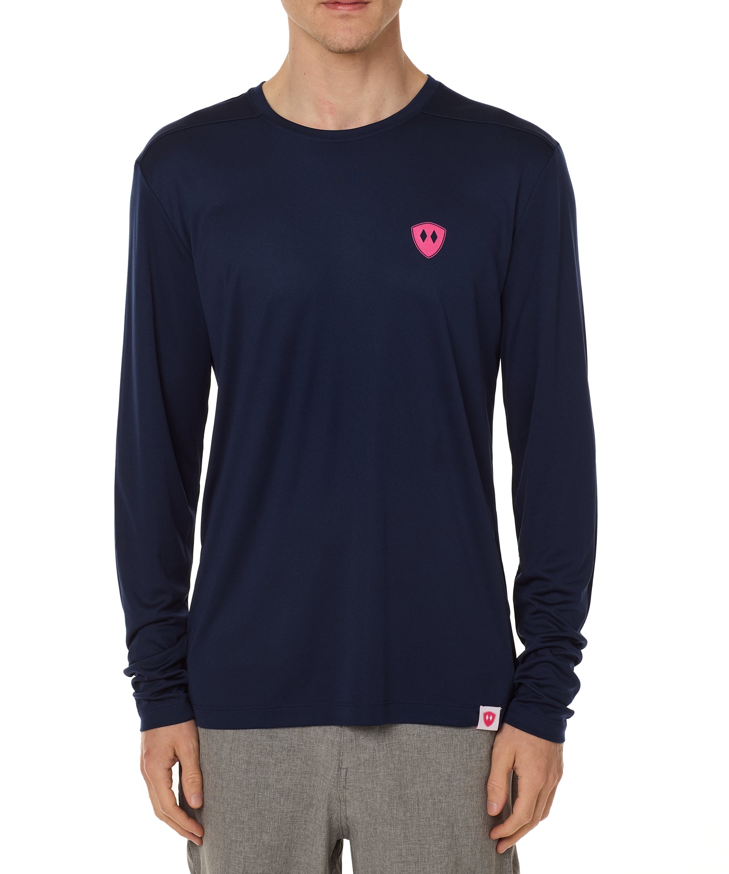 Front view of a male model wearing the Skull Wave Head performance long sleeve tee in Navy on a white background. Accented with a hot pink double diamond shield over wearers left chest.