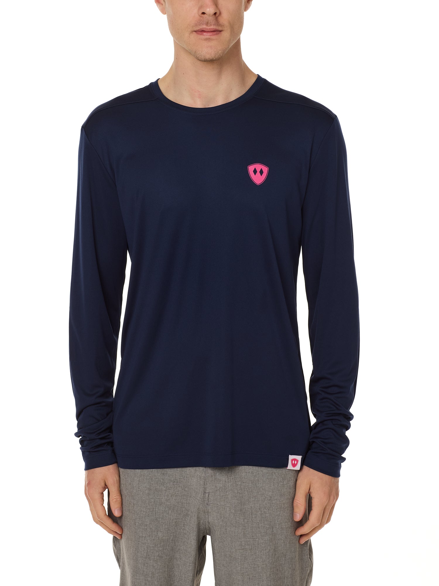 Front view of a male model wearing the Skull Wave Head performance long sleeve tee in Navy on a white background. Accented with a hot pink double diamond shield over wearers left chest.